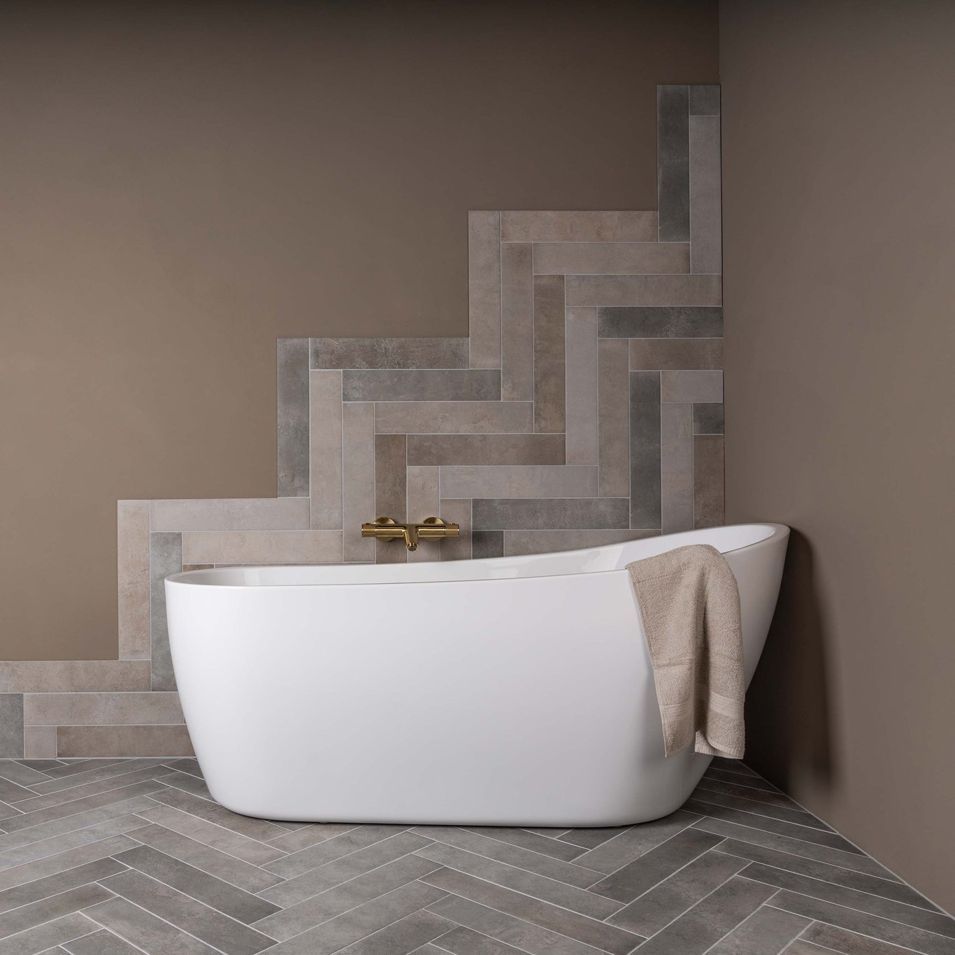 Baderom med badekar i front. Blanding av beige fliser og brun mikrosement på vegg.